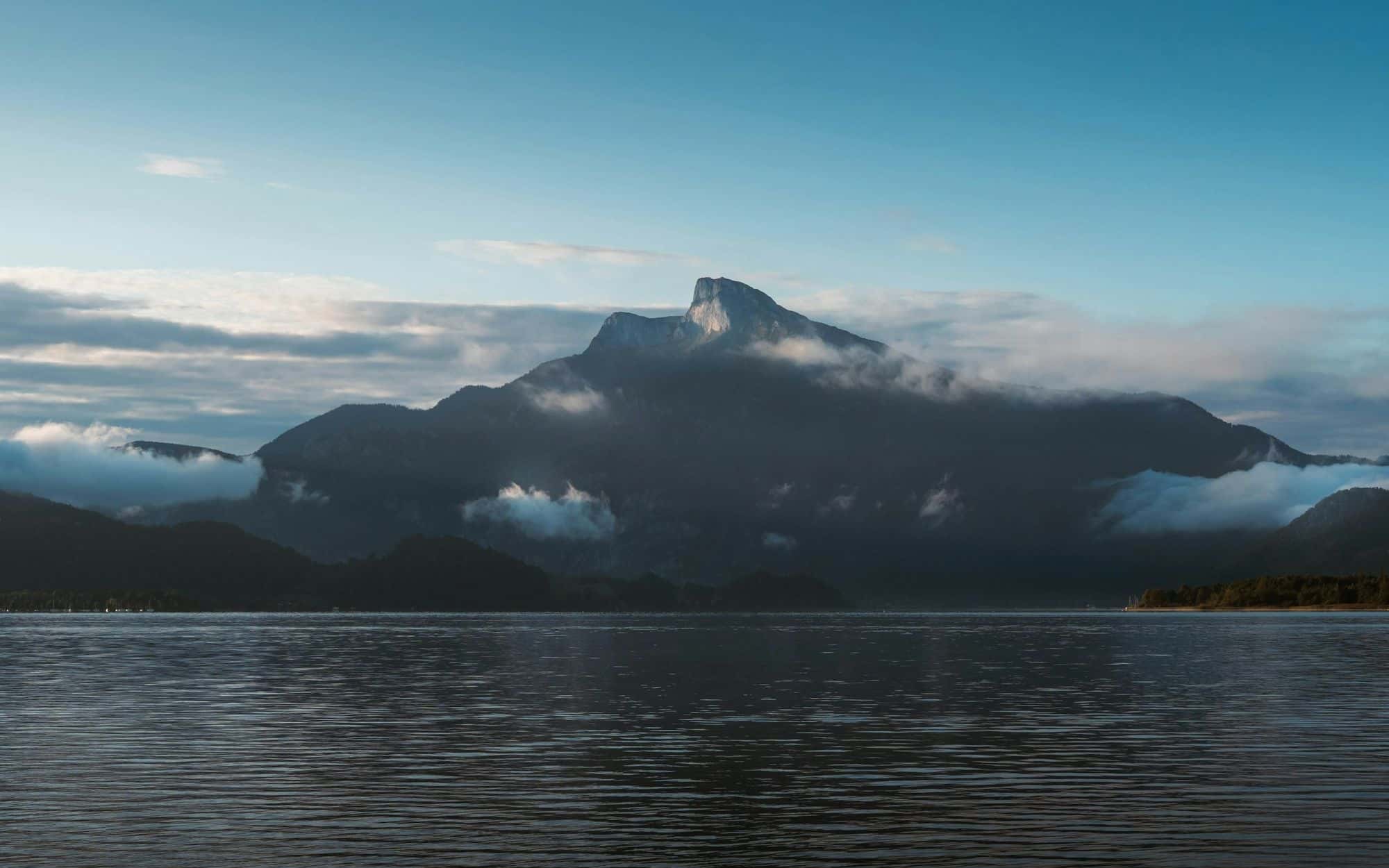 A misty mountain peak above a still lake at dawn
