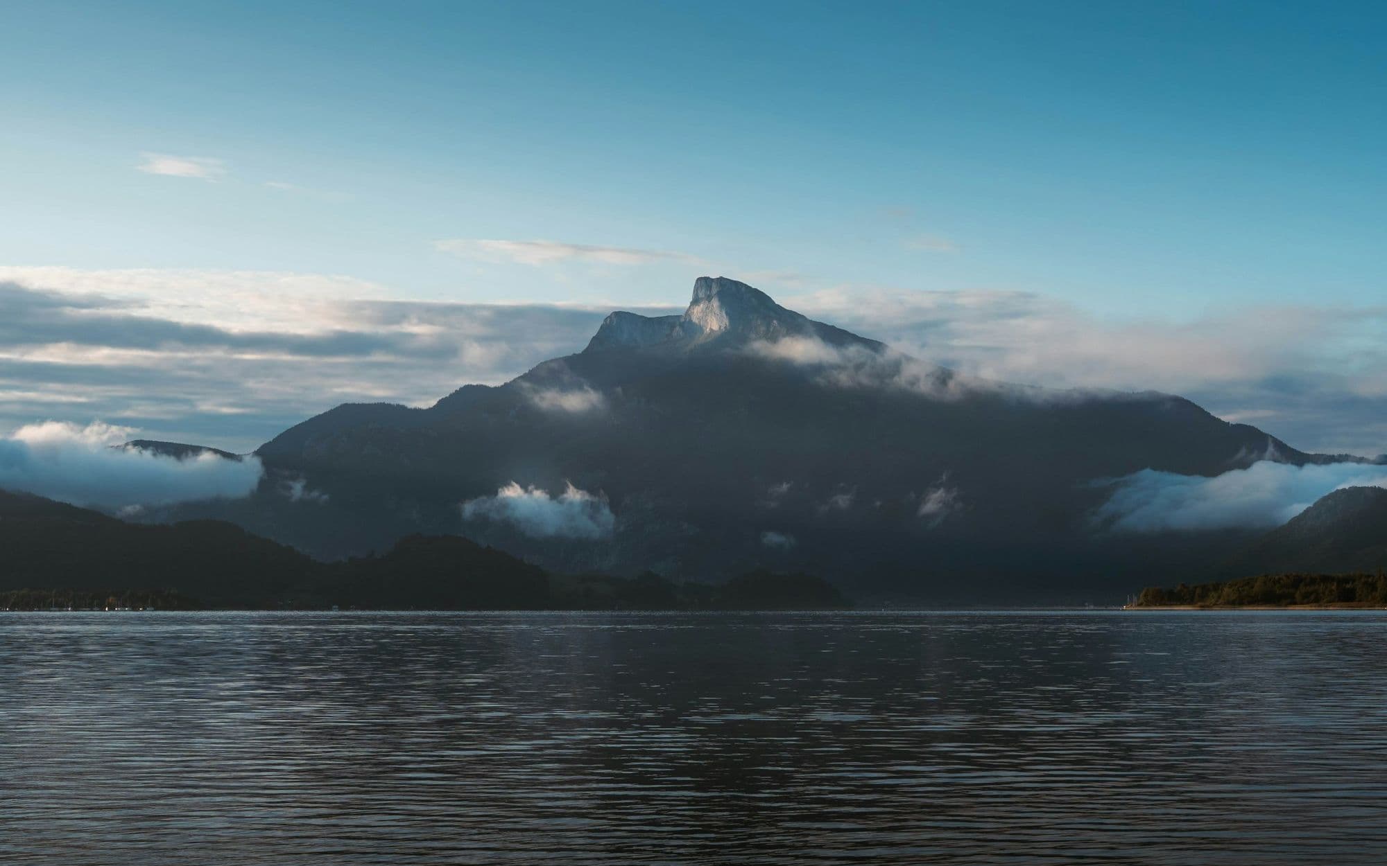 A misty mountain peak above a still lake at dawn