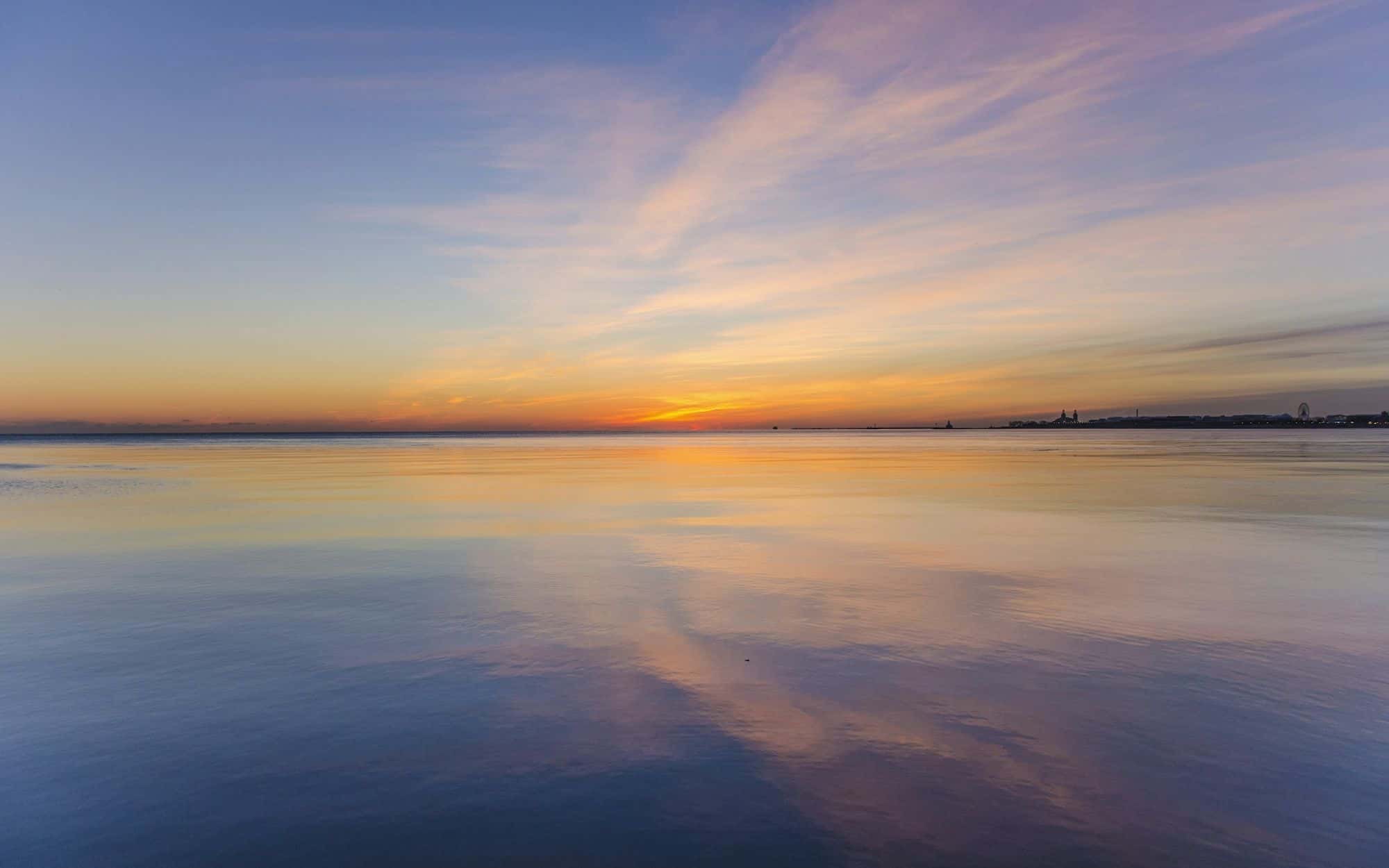 Calm water reflecting a soft pastel sky at dusk