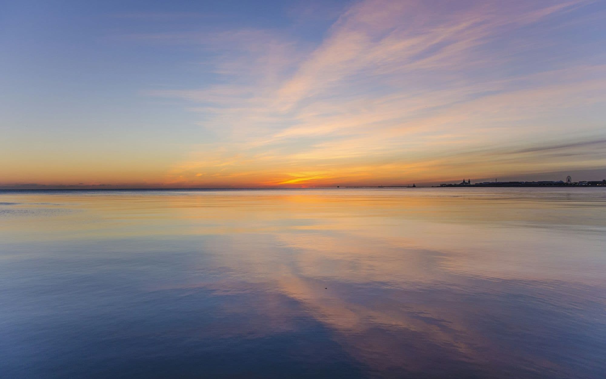 Calm water reflecting a soft pastel sky at dusk