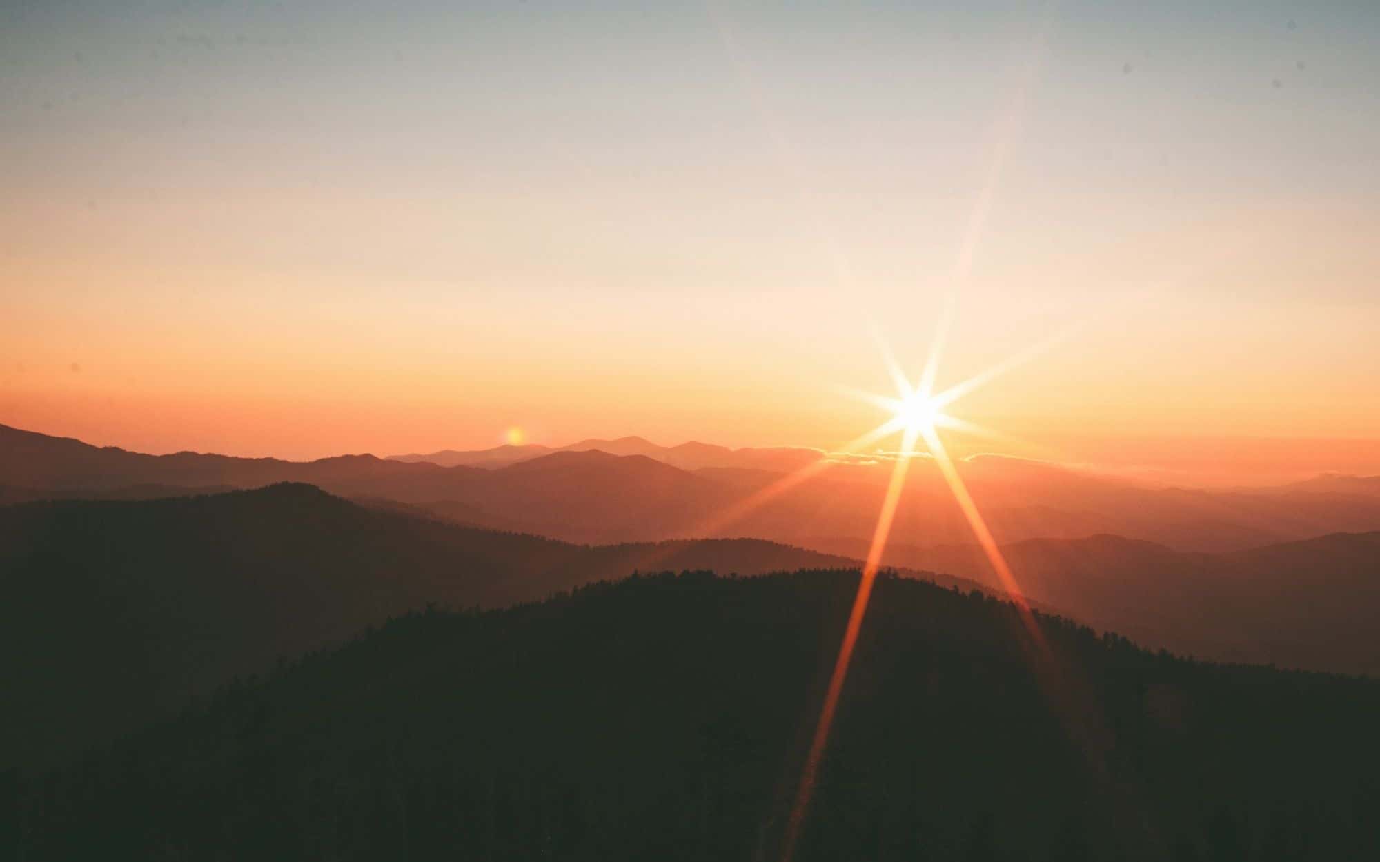 Layered mountain ridges fading into a sunset haze
