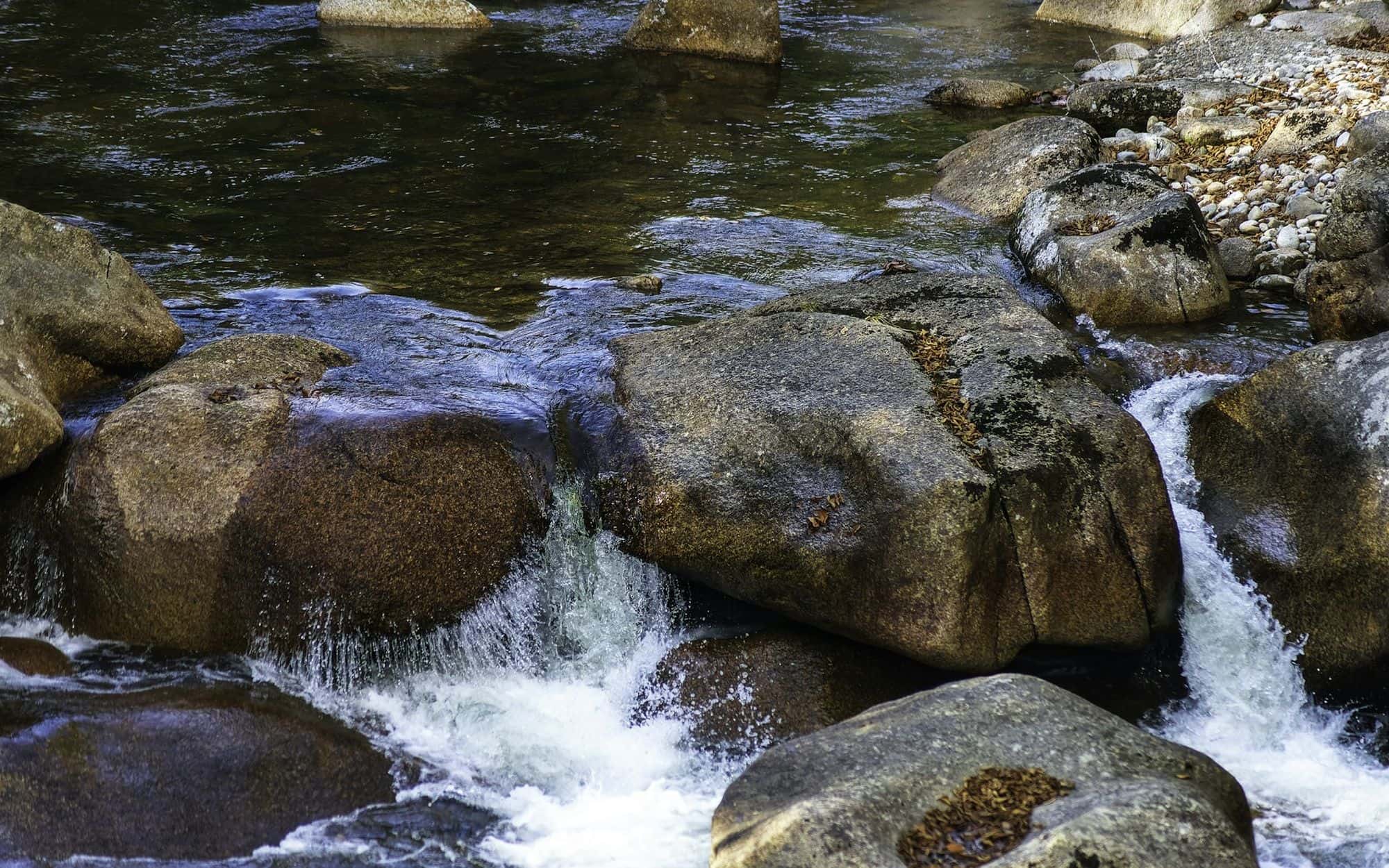 Clear water rushing over rounded granite stones