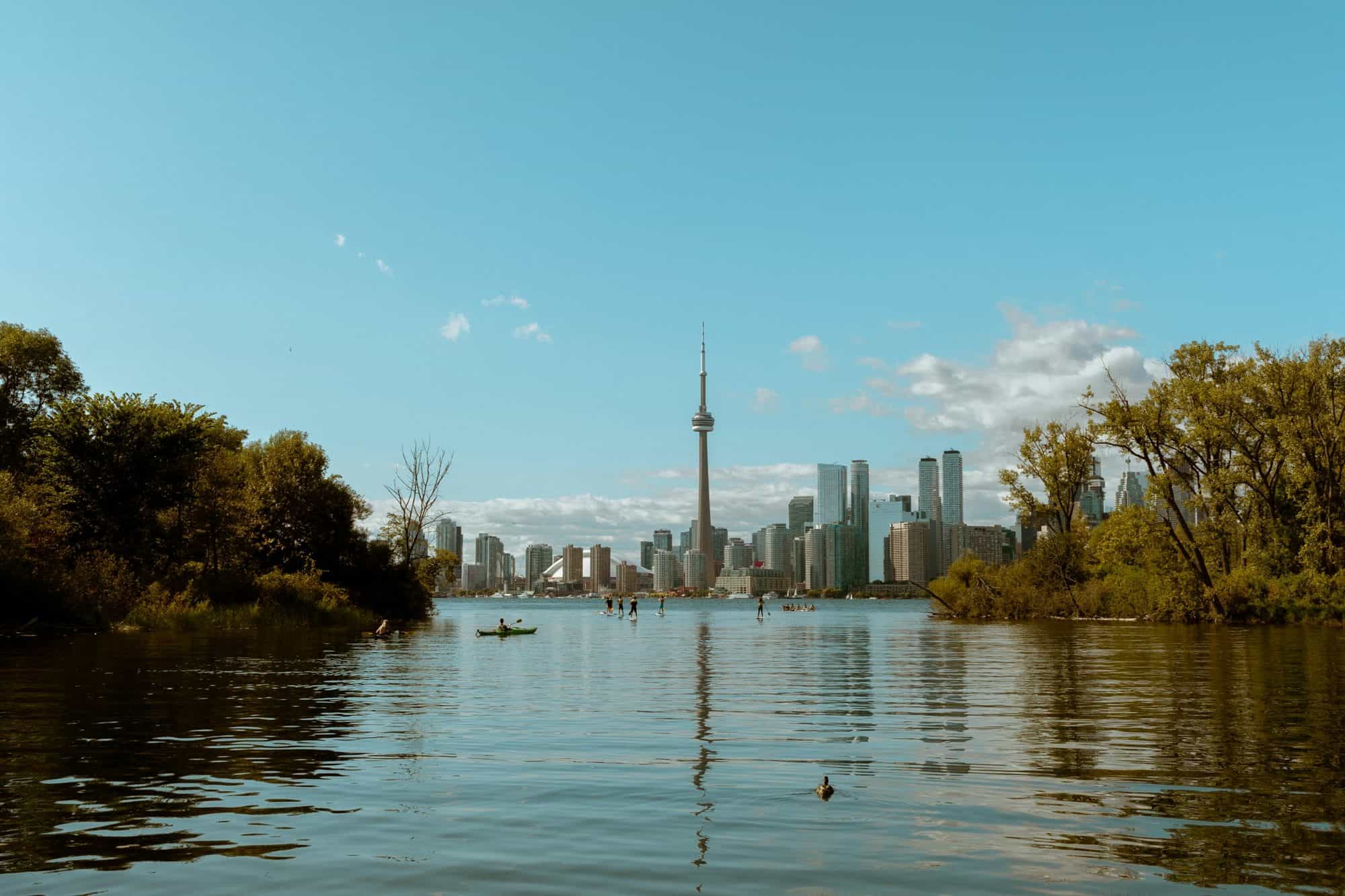 Toronto skyline and CN Tower seen across calm water from Toronto Island