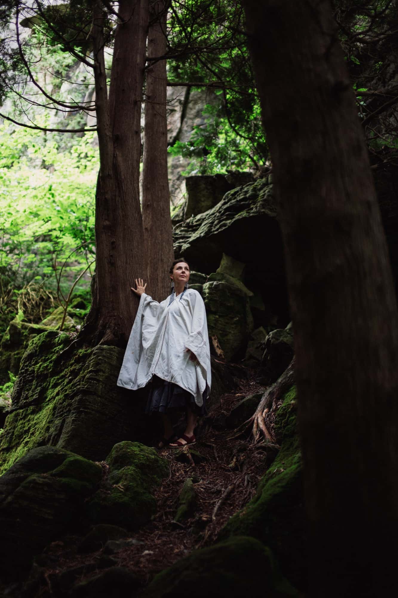 Mariya Garnet smiling warmly toward the camera in forest light